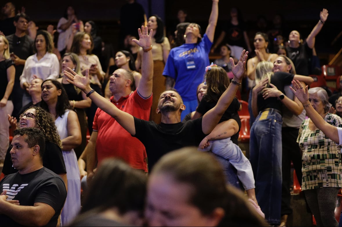 A room of believers with hands raised in worship