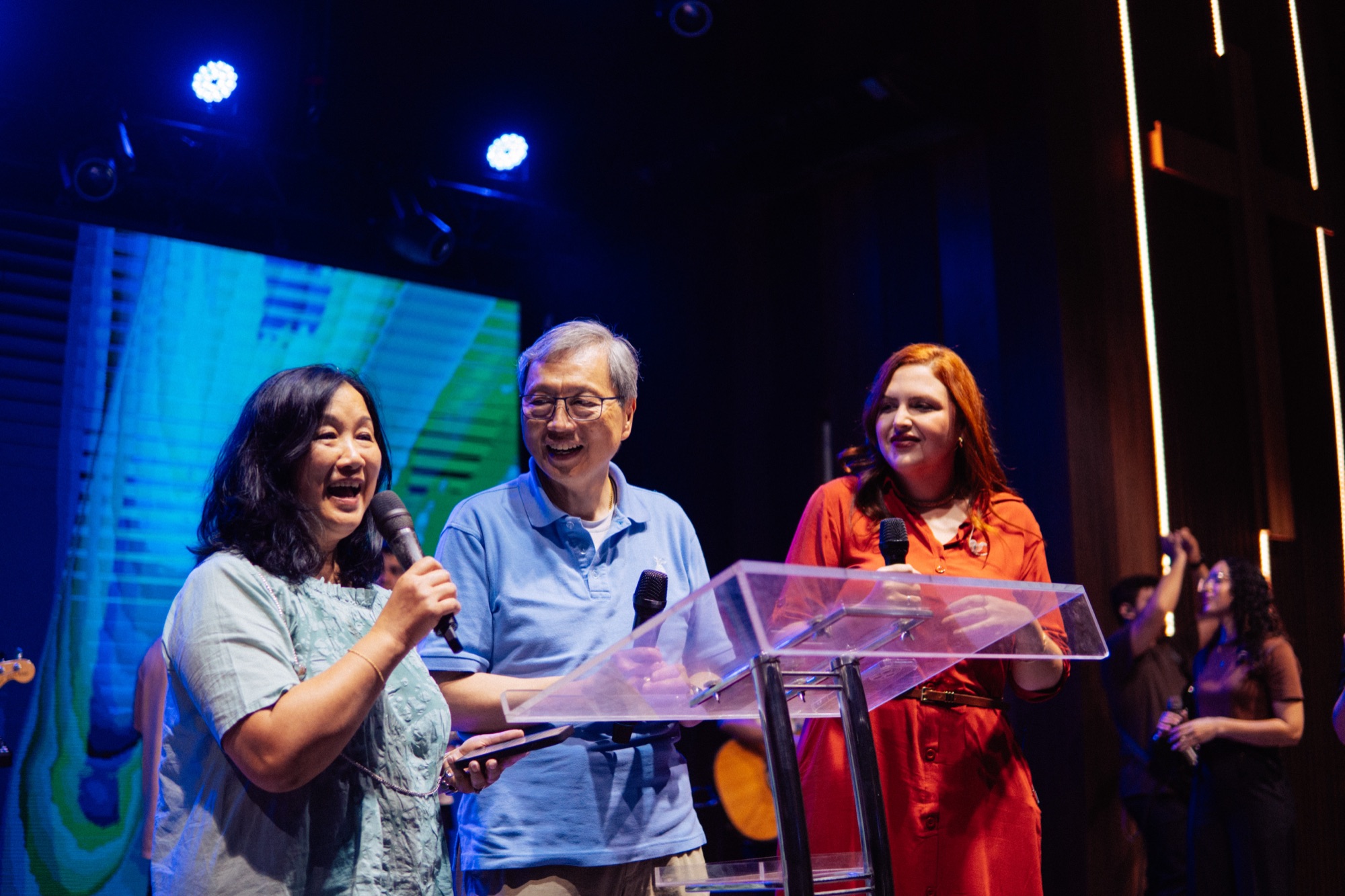 A trio leading worship on stage with microphones