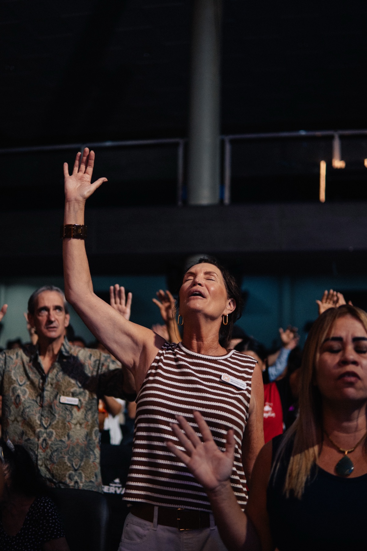 A woman worshipping with her hand raised and eyes closed