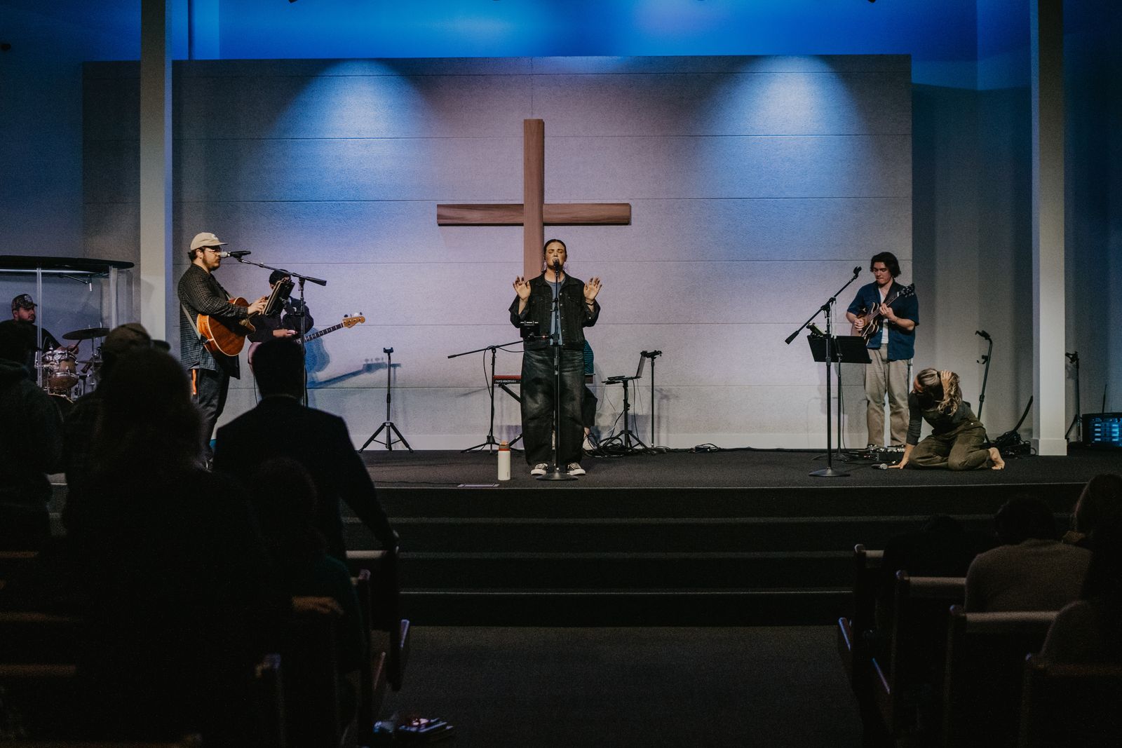 The worship team on stage beneath a wooden cross