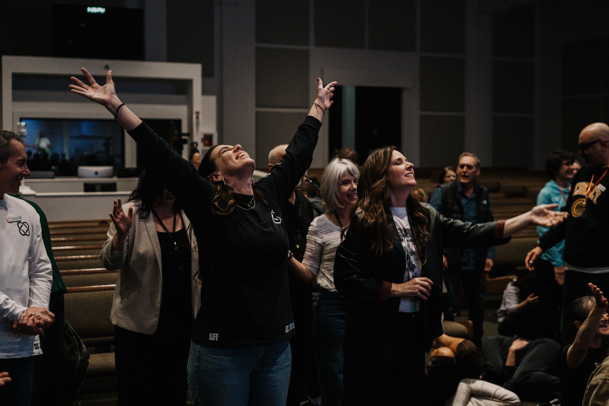 A room full of people with hands raised in worship